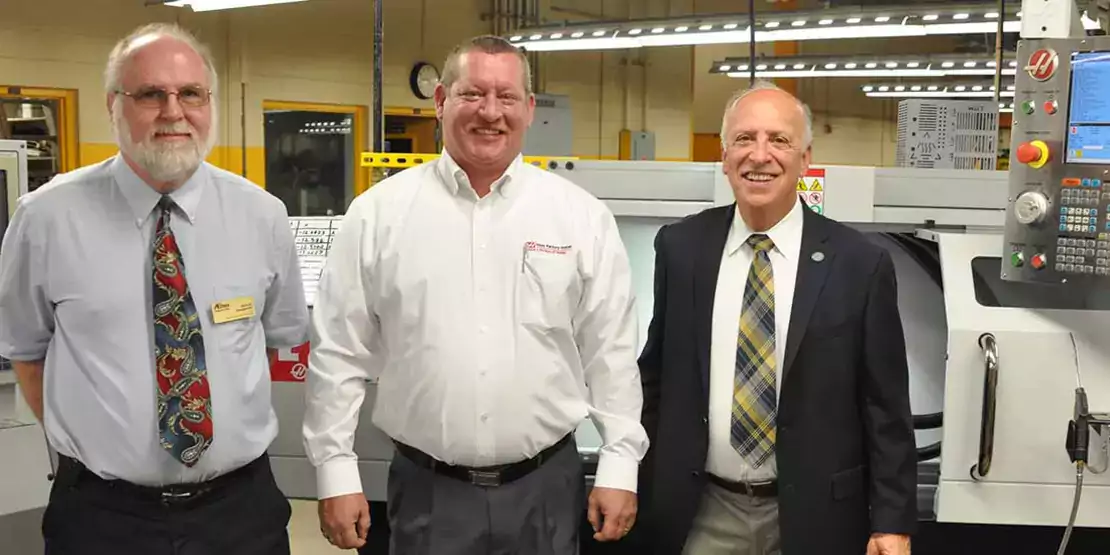 Three men in front of a CNC machine