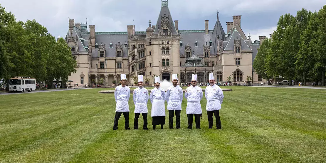 six chefs standing on a lawn in front of the Biltmore House