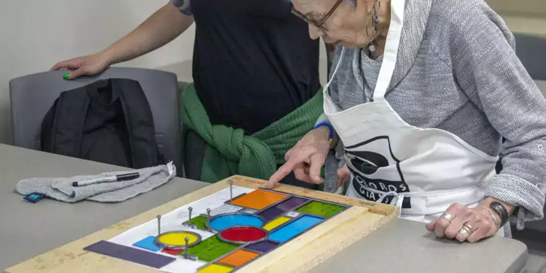 Older woman with stained glass project on table