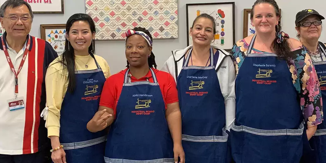 Six men and women in blue aprons standing