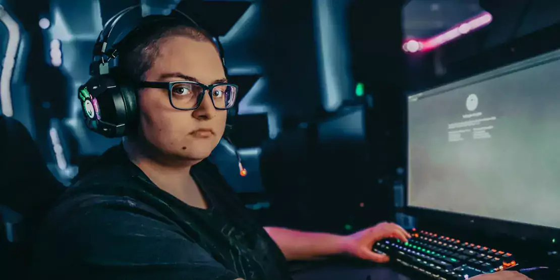 Person sitting at a desk with a computer wearing headphones