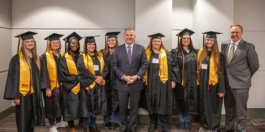 Student inmates pose for graduation photo with state governor and college president.