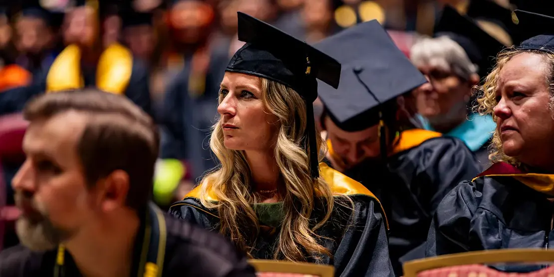 A-B Tech graduates listen as Gov. Josh Stein speaks inside Harrah's Cherokee Center during the university's graduation ceremony, May 10, 2025, in Asheville.