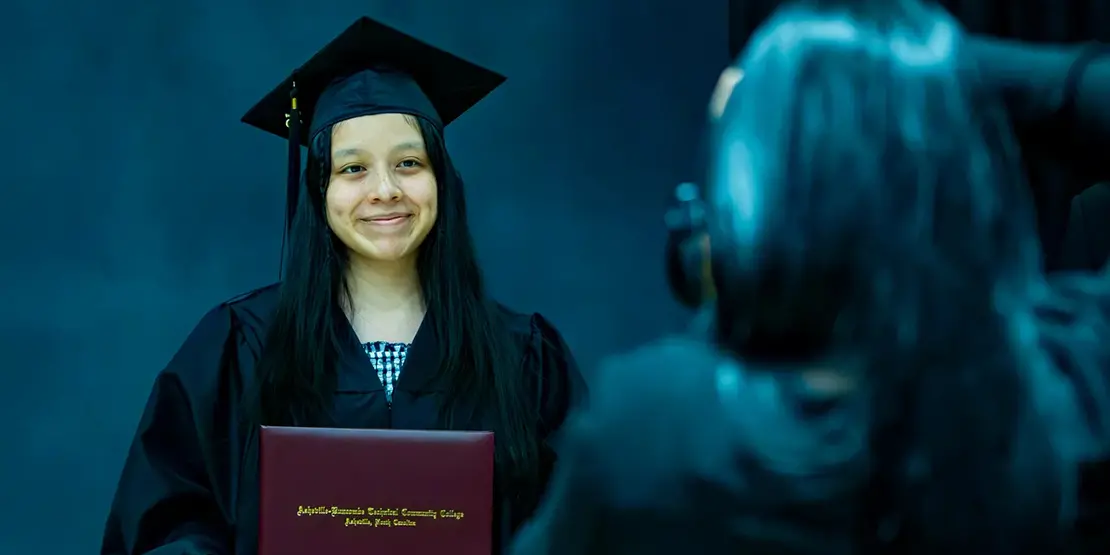 A-B Tech graduates pose for photos with their diplomas inside Harrah's Cherokee Center during the university's graduation ceremony, May 10, 2025, in Asheville.