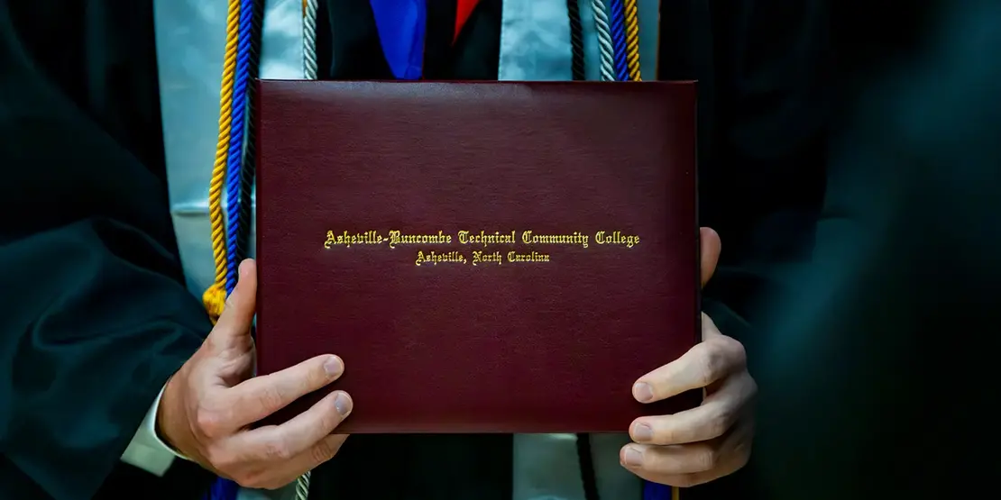 A-B Tech graduates pose for photos with their diplomas inside Harrah's Cherokee Center during the university's graduation ceremony, May 10, 2025, in Asheville.