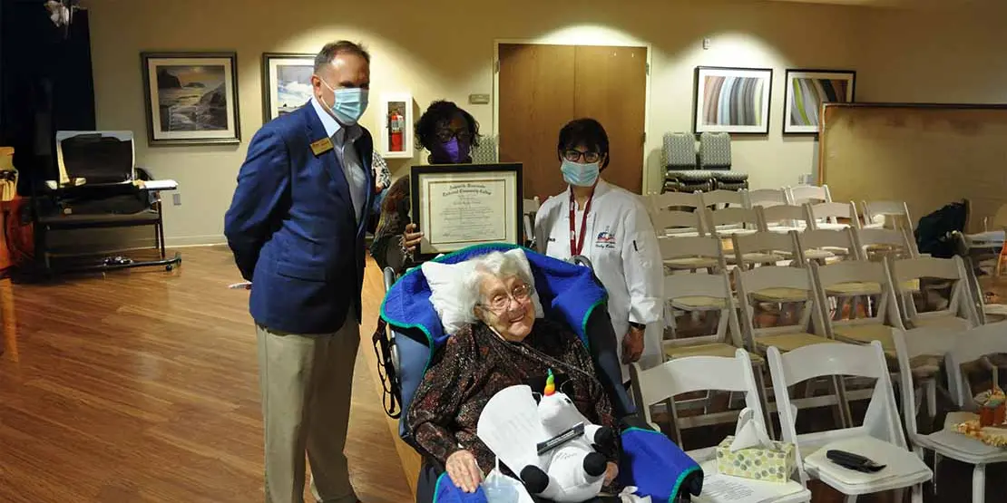A woman in a wheelchair with 3 people standing behind her. 