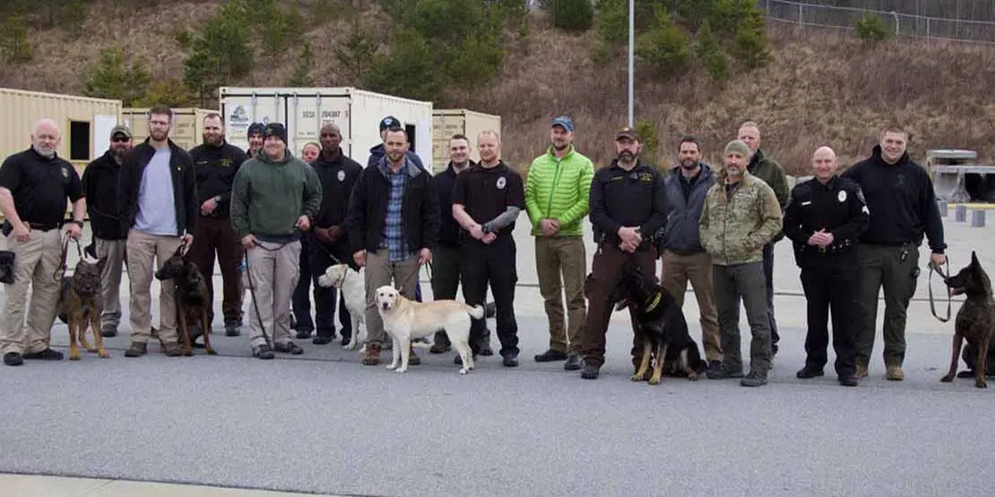 Handlers and their dogs standing outside