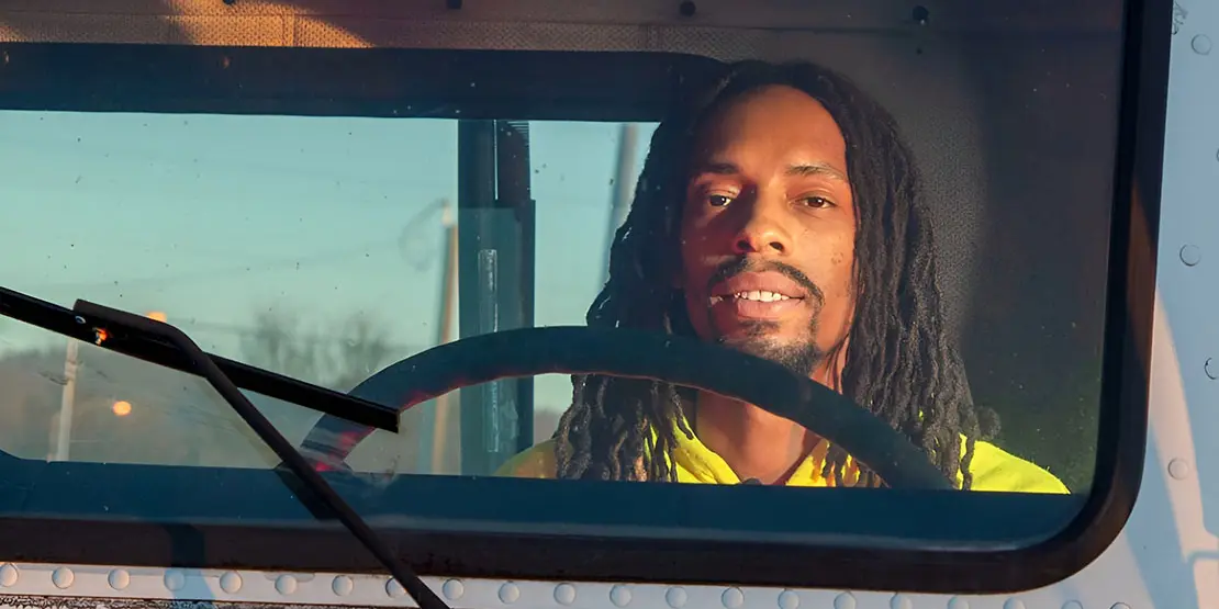 Man wearing yellow shirt sitting in the cab of a truck