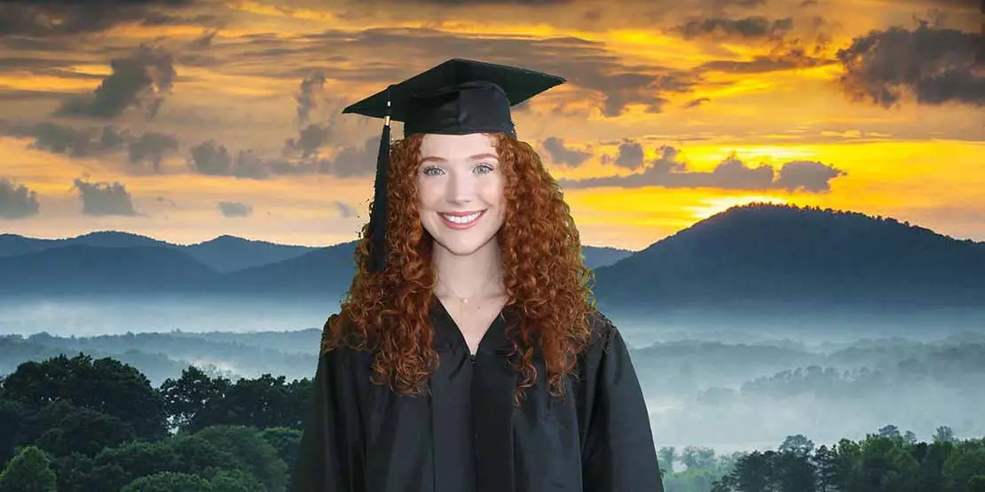 Woman in cap and gown in front of mountains