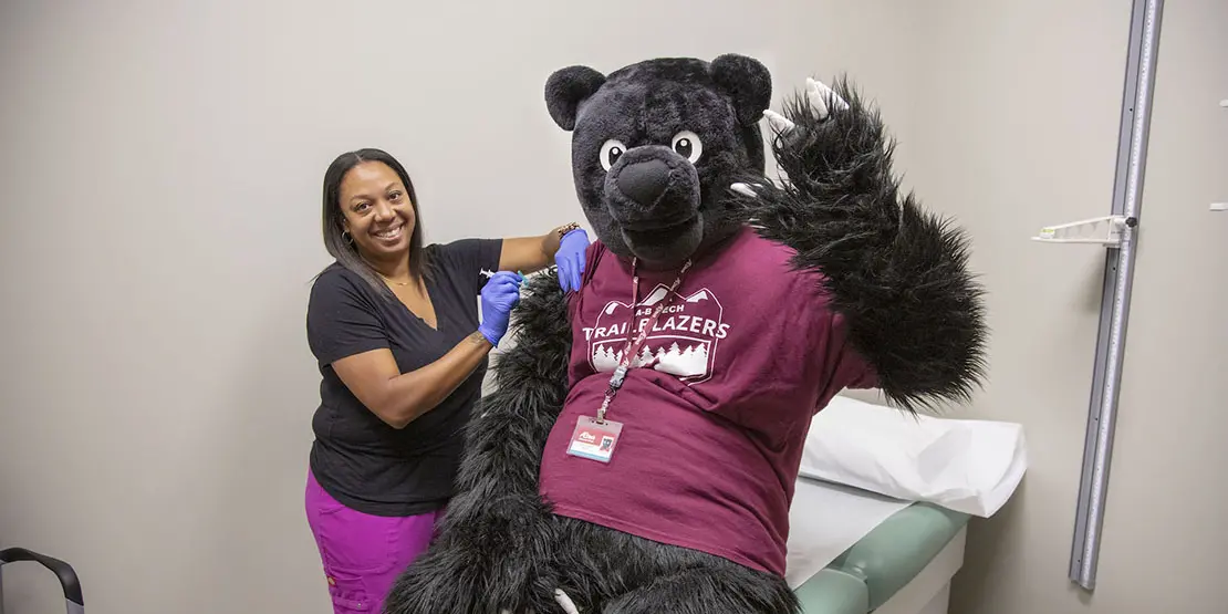 Trailblazer Bear receiving a vaccine from the health clinic