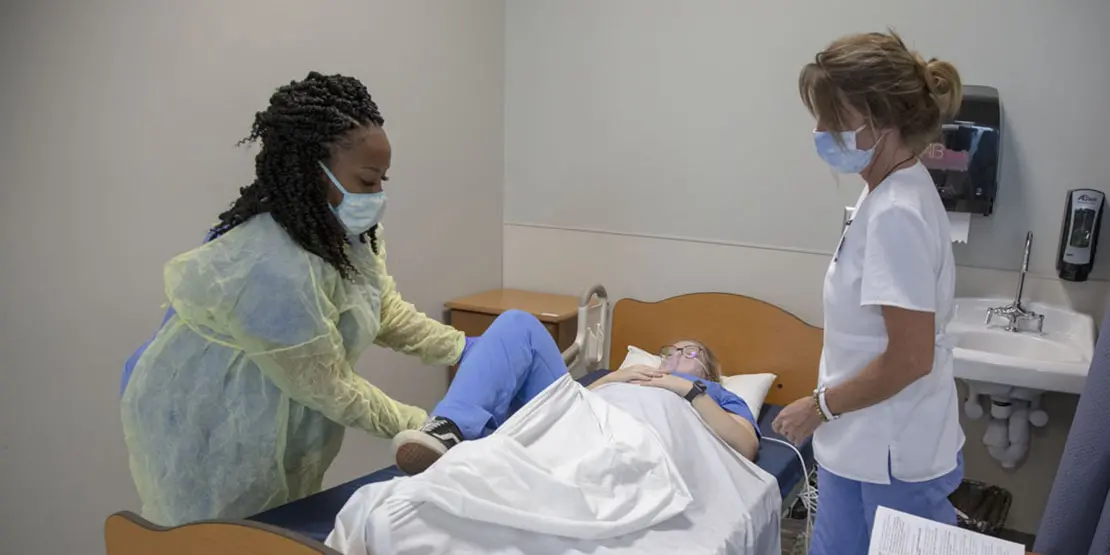 Two women standing by an occupied hospital bed