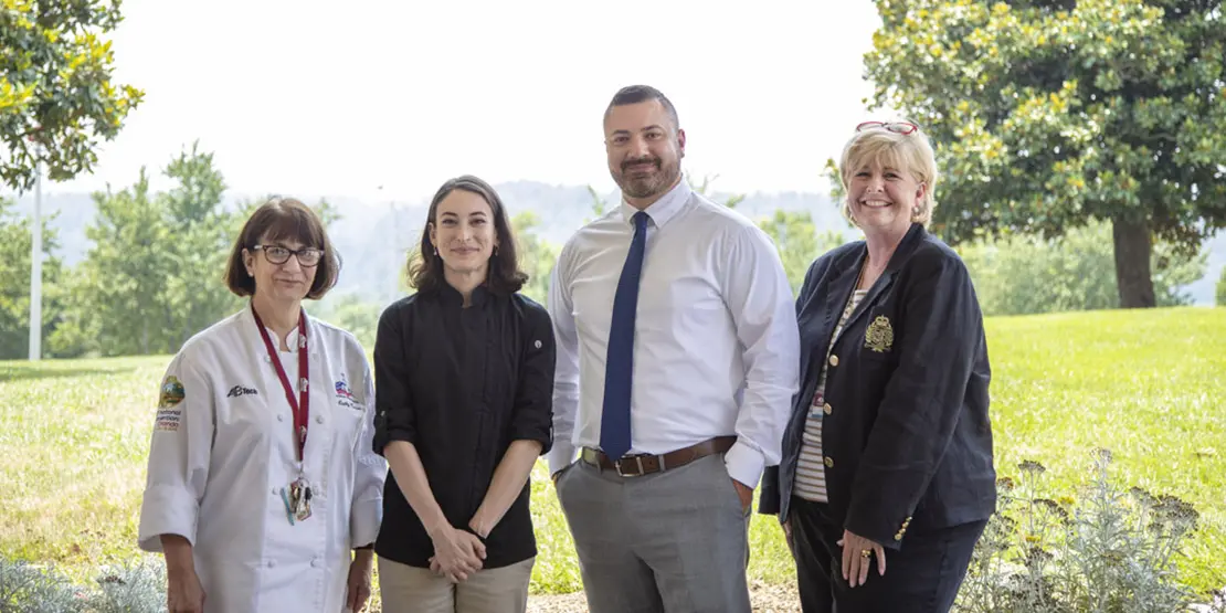 Four people standing outside near trees