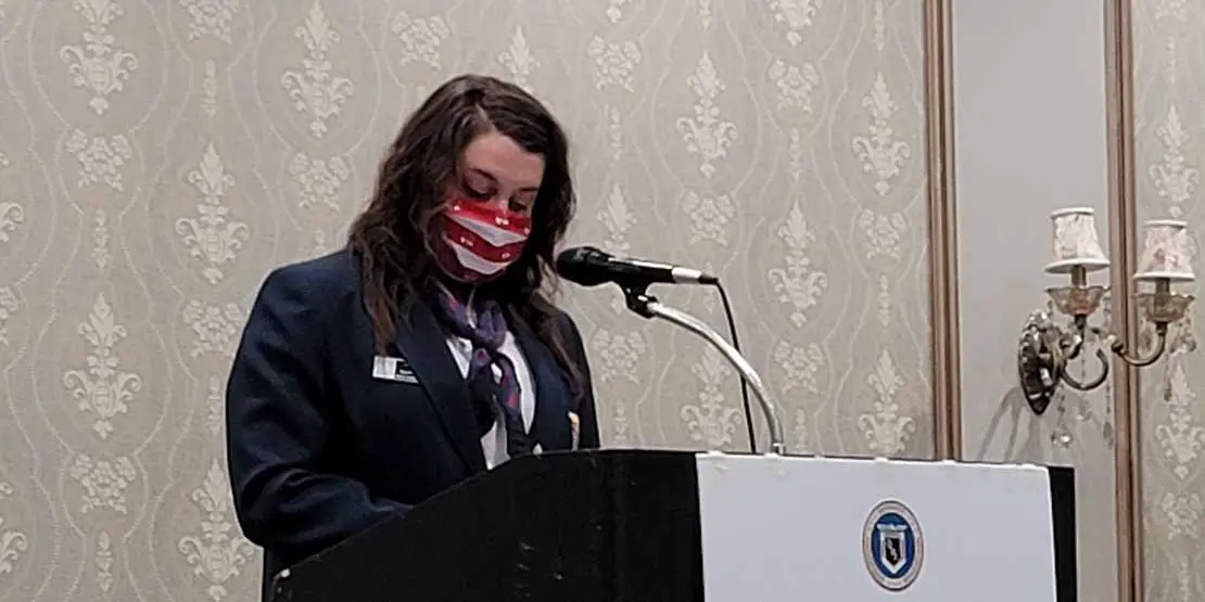 Woman in a face mask standing behind a lectern