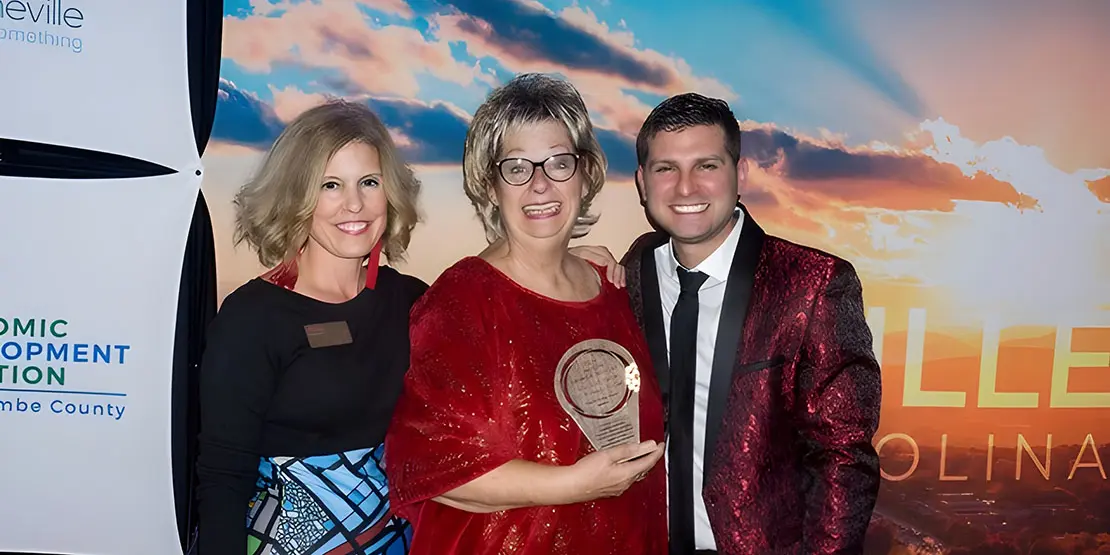 Two women and a man with an award