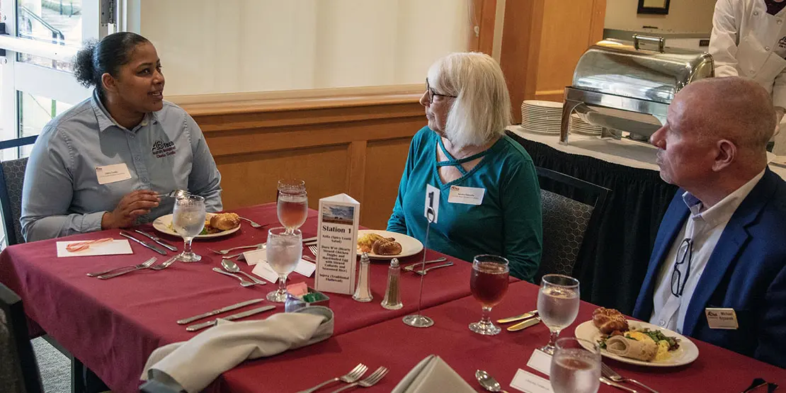 Student eating lunch with two donors