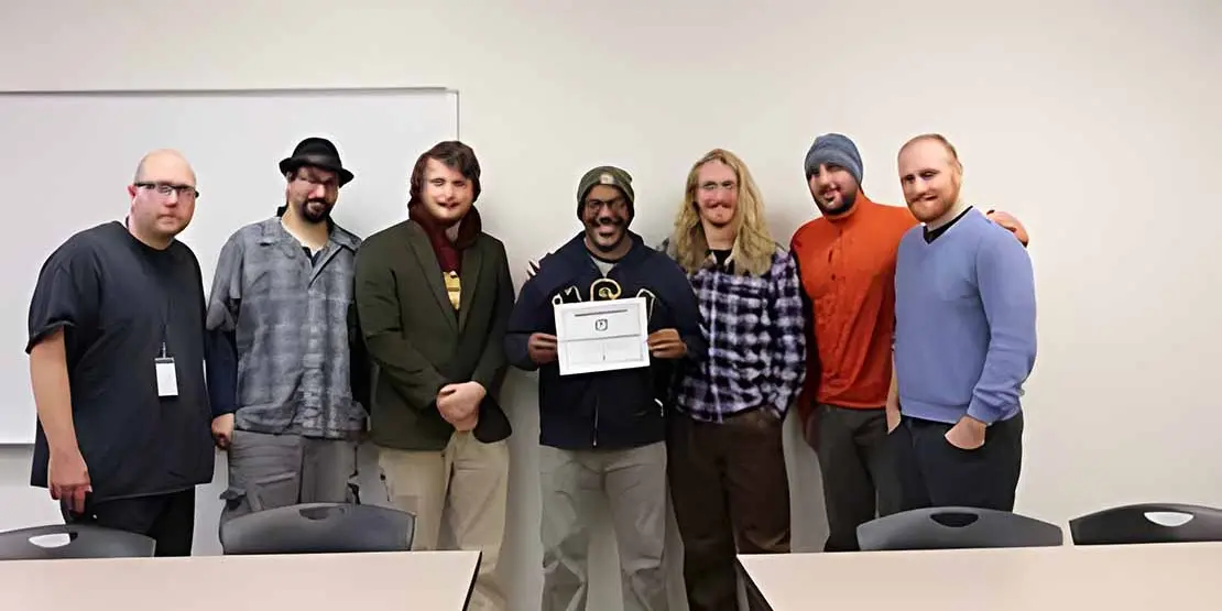 Heath Moody and his students in the Issues In Sustainability class against a wall with a certificate.