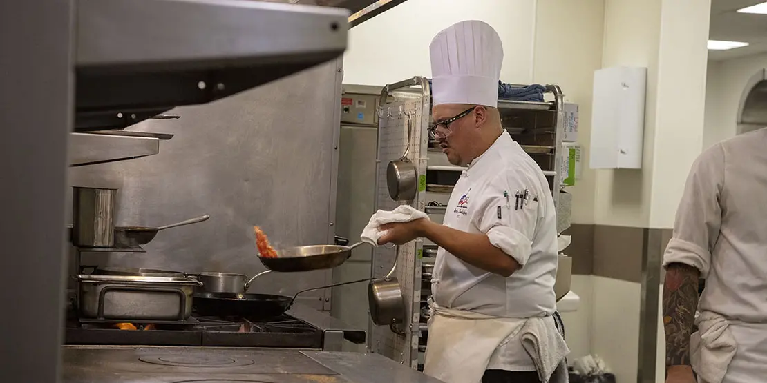 Chef with frying pan in front of stove