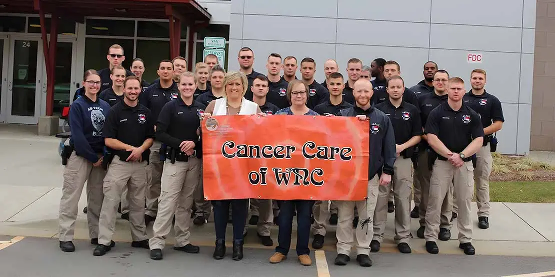 28 students and two women holding a banner reading Cancer Care of WNC