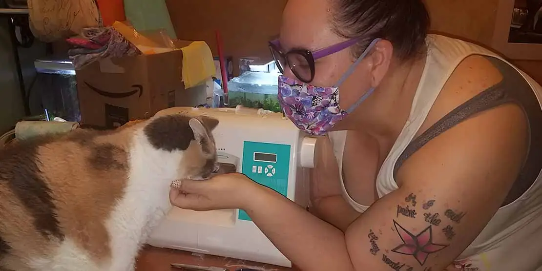 Porscha Orndorff at her sewing machine with a cat.