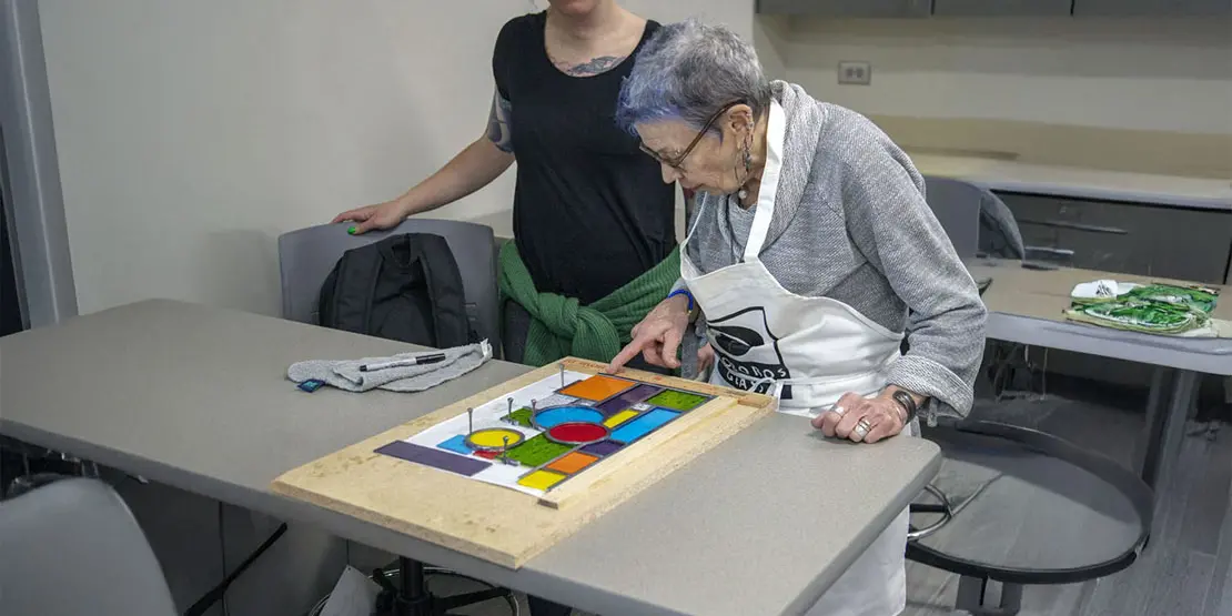 Older woman with stained glass project on table