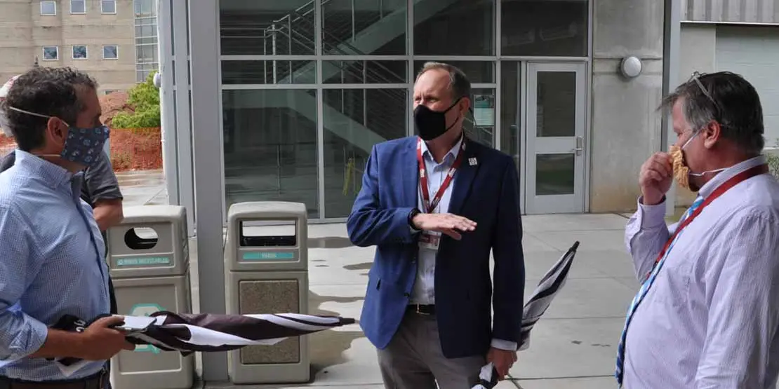 Three men wearing masks and talking