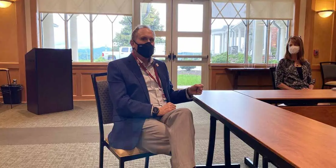 Man sitting at table wearing mask and orange checkerboard socks
