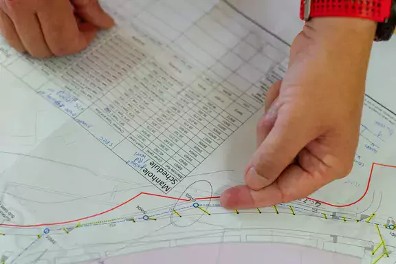 Hand pointing at a spot on a schematics paper