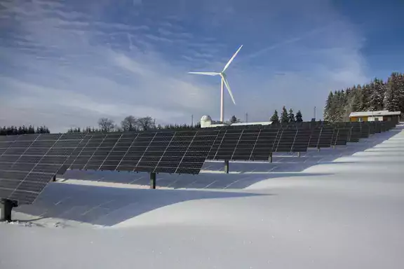 solar panels with a wind turbine in the background