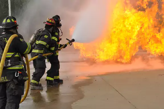 Two firefighters fighting a blaze with a hose