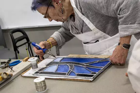 woman working a blue stained glass