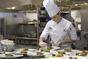 Female culinary student preparing plates