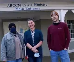 Three students standing in front of a white building