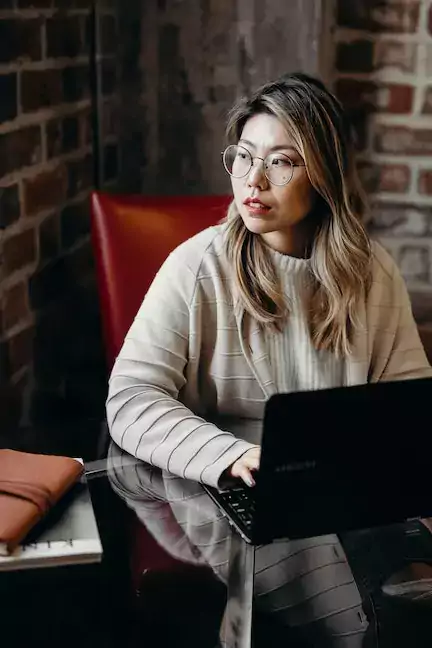 Woman sitting in a red chair with a laptop on a table in front of her