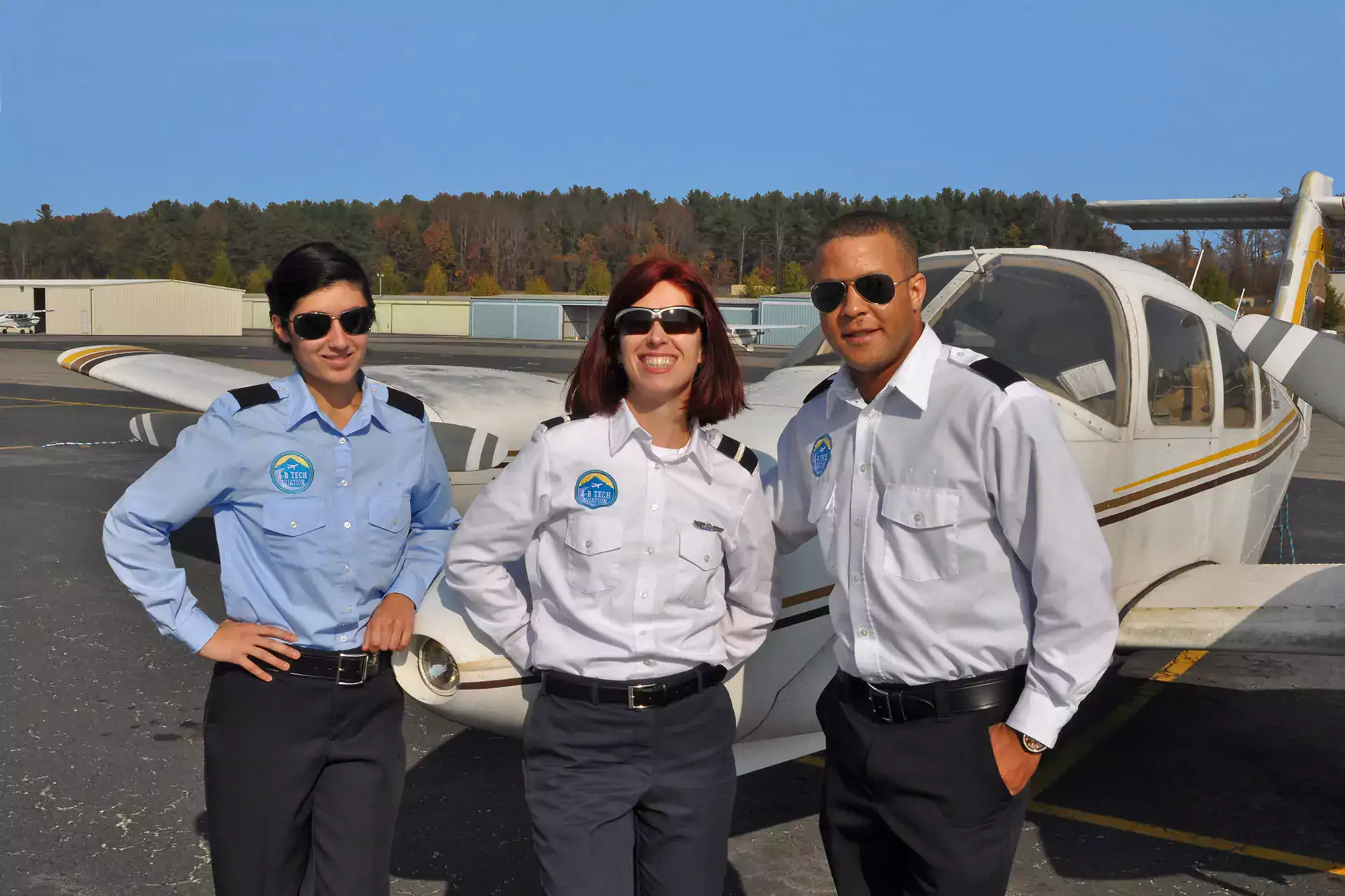 Three pilots in uniform standing in front of a plane
