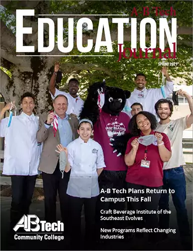 Dr. Gossett, Trailblazer bear and students standing under a tree