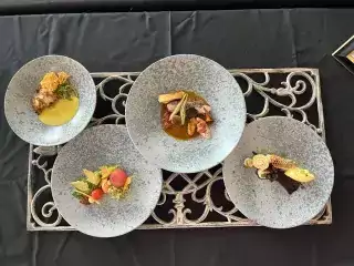 Four plates holding food on a black tablecloth