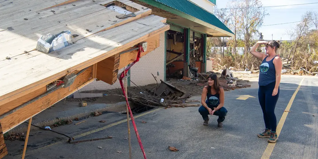 Sisters Jessie, left, and Melissa Dean look at a portion of their production facility, October 31, 2024, in Asheville. The building flowed nearly a mile down the Swannanoa River to Asaka Japanese Cuisines during Tropical Storm Helene.