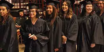 Six graduates in caps and gowns at commencement.