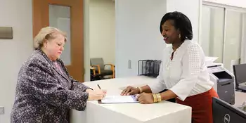 Office Assistant at a desk with a patient