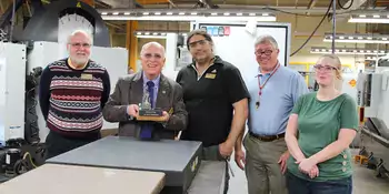 Dennis King holding a miniature engine lathe with 4 other people