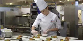 Student chef preparing plates of food.