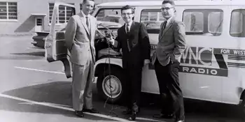 Three men in front of a radio broadcasting van