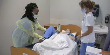 Two women standing by an occupied hospital bed