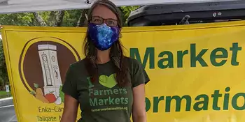 Woman wearing a mask in farmers market booth 