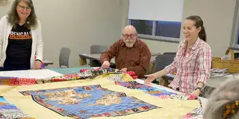 Three people at a table with a quilt