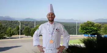 A chef wearing his uniform with a medal around his neck. 