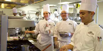 Three culinary students at a stove