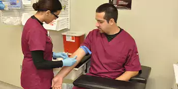 Woman drawing blood from the arm of a man