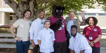 A group of students with Dr. Gossett and Trailblazer bear on a deck
