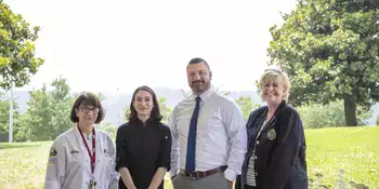 Four people standing outside near trees